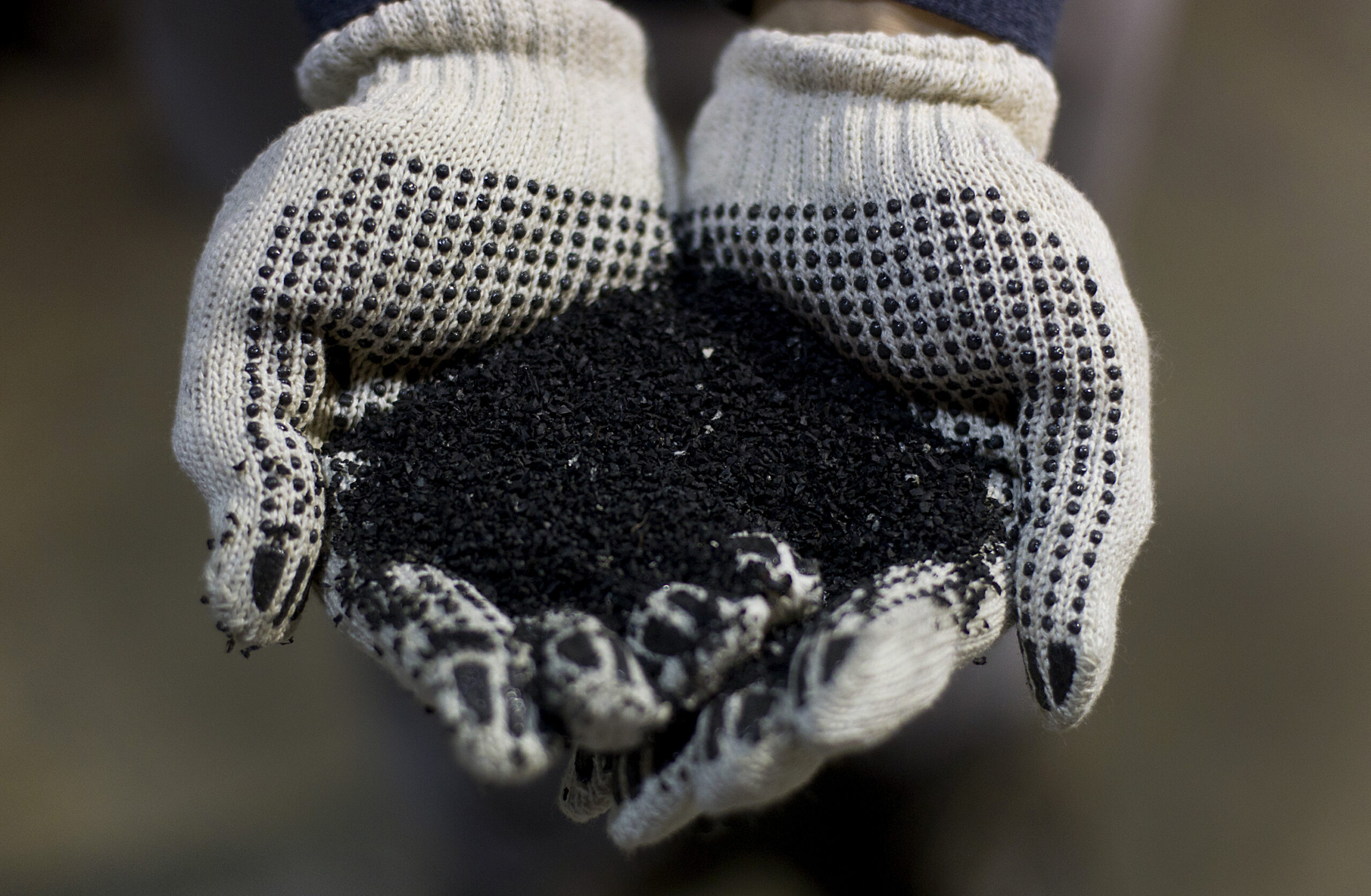 A worker displays crumb rubber at a tire recycling facility